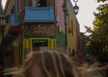 a girl turns her head against the backdrop of a multi-coloured building