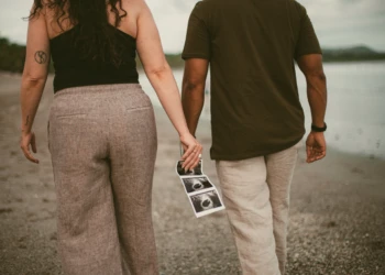 Couple walking barefoot along Sámara beach during their engagement photoshoot